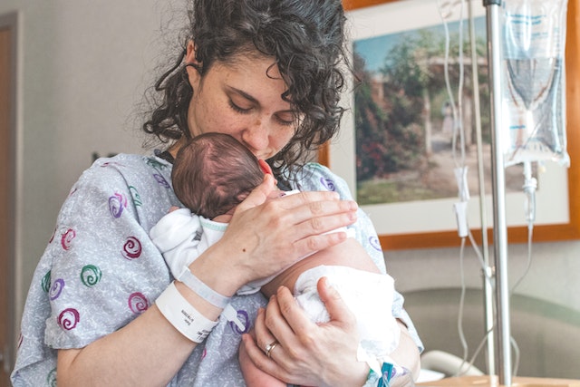 Mama po cesarskim cięciu trzyma na rękach noworodka